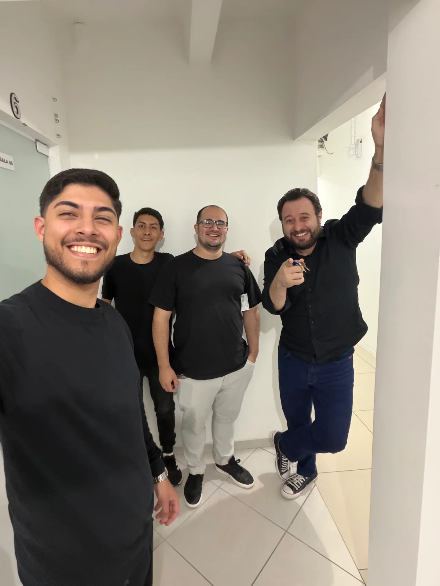 Quatro pessoas reunidas em um corredor, em uma foto descontraída dos bastidores.