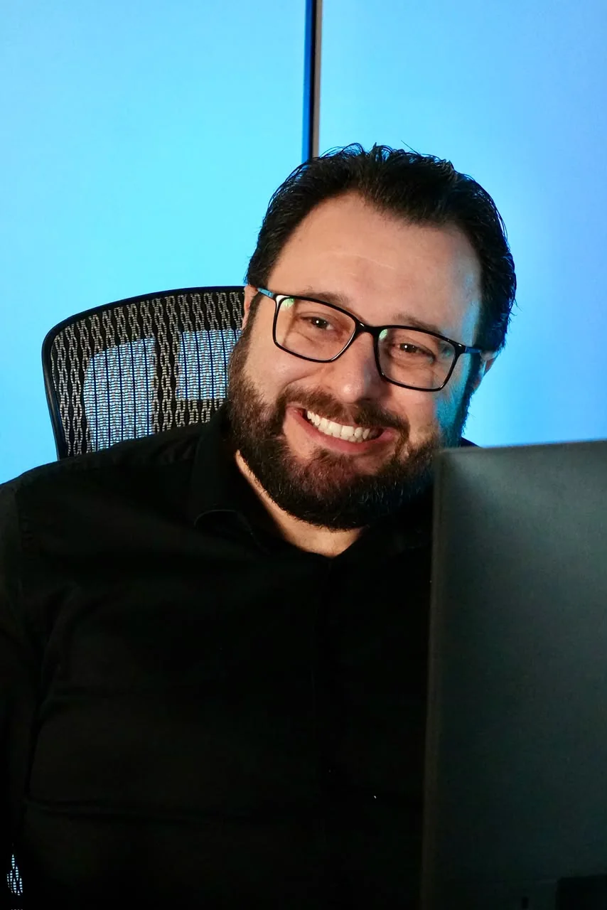 Joviano de óculos, sorrindo durante uma conversa.
