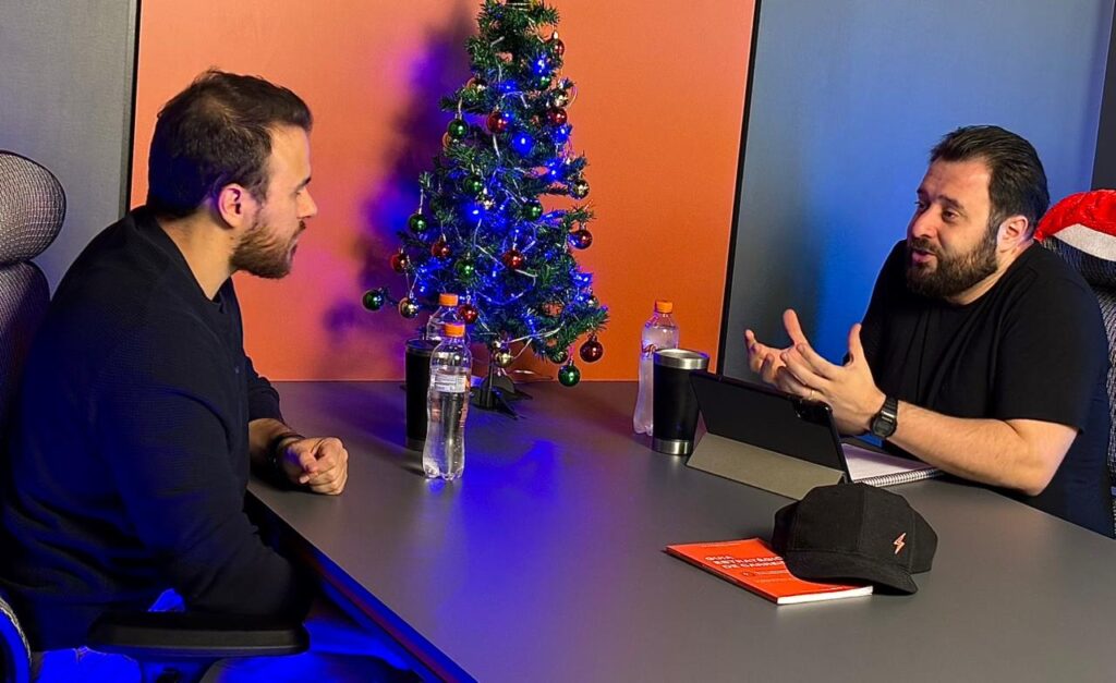 Joviano e convidado na mesa do podcast com decoração de Natal.